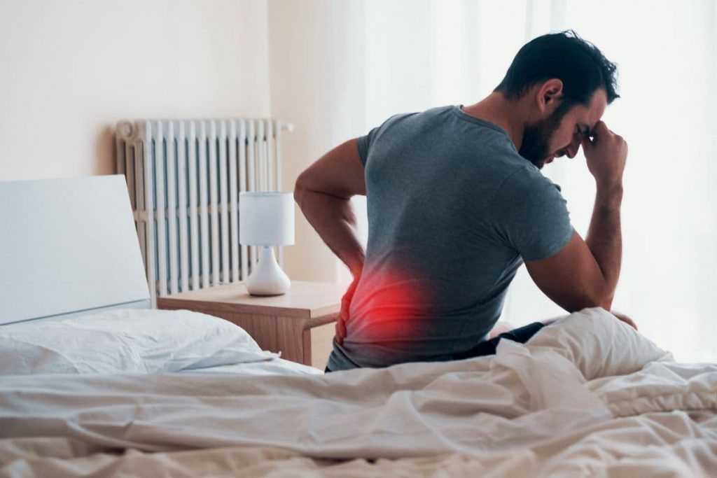 man getting out of bed with back pain